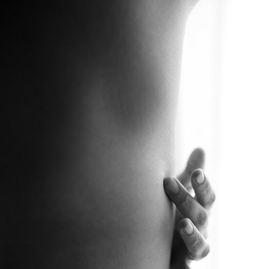 Foto in bianco e nero di una mano che accarezza il corpo. Fotografia boudoir Trieste