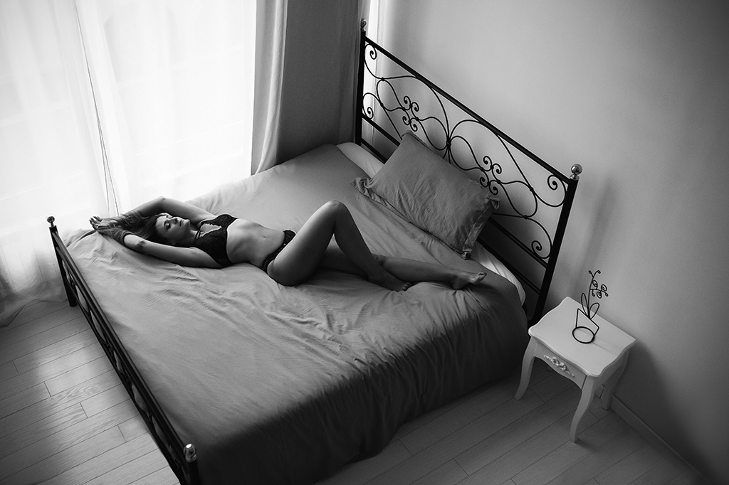 Foto in bianco e nero di una donna in initmo nero, distesa a letto. Fotografia donna in initimo sensuale boudoir Italia
