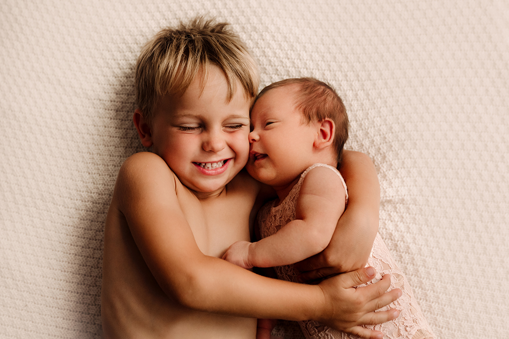 Foto di famiglia a colori, in cui il fratello abbraccia il neonato. Fotografia a colori di famiglia fratello con neonato Italia