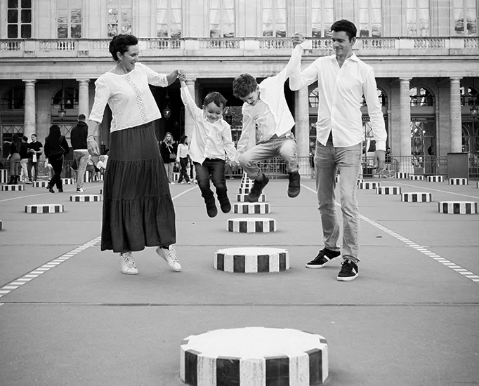 Foto in bianco e nero fuori studio a Parigi, di una famiglia che gioca. Fotografia in bianco e nero di una famiglia a Parigi Trieste