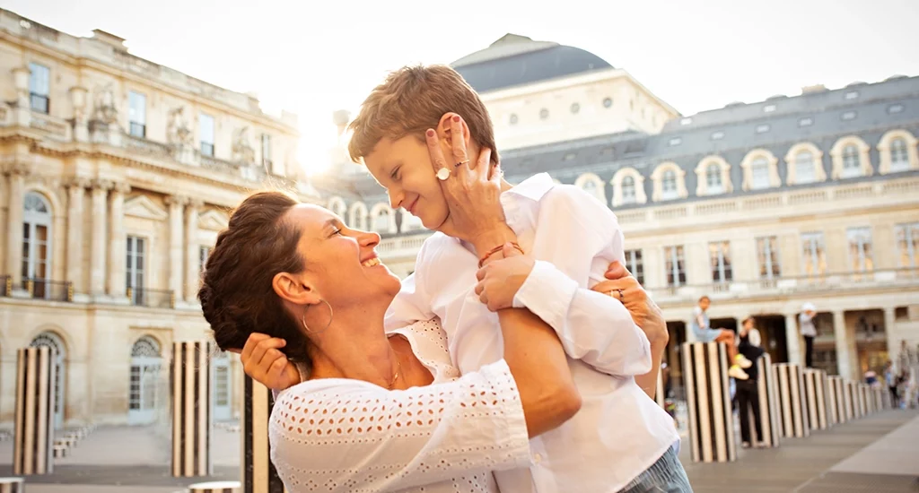 Foto a colori fuori studio a Parigi, di una mamma con il figlio che si abbracciano. Fotografia a colori di una famiglia a Parigi Italia
