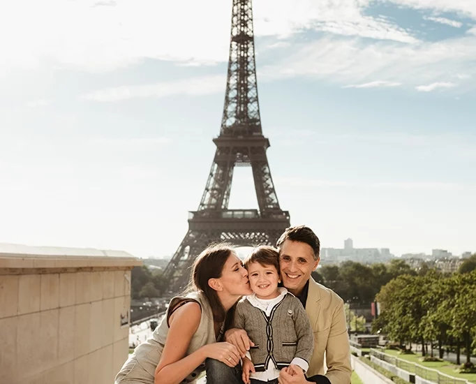 Foto a colori fuori studio a Parigi, di una famiglia che si abbraccia ridendo tutti insieme. Fotografia a colori di una famiglia a Parigi Italia