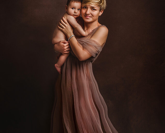 Foto a colori in studio di famiglia, di una mamma con un abito lungo, con il figlio nudo in braccio. Fotografia a colori di famiglia mamma e figlio Trieste