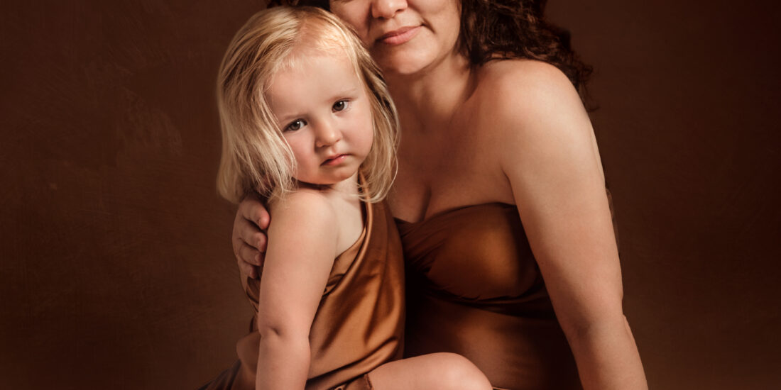Foto a colori in studio di famiglia, di una mamma con la figlia in braccio. Fotografia a colori di famiglia mamma e bambina Italia