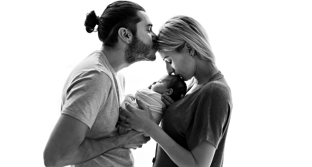 Foto di famiglia in bianco e nero, in cui i genitori tengono in braccio. Fotografia in bianco e nero di famiglia con neonato Italia