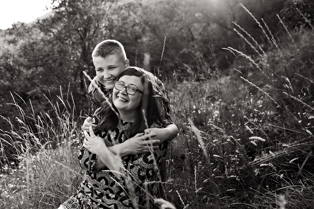 Foto fuori studio in bianco e nero di una donna con un bambino che la abbraccia ed entrambi sorridono. Fotografia fuori studio di una donna un bambino in bianco e nero Trieste