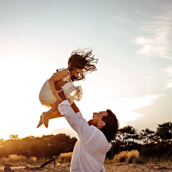 Foto a colori fuori studio al tramontare del sole con padre che tiene la figlia tra le mani. Fotografia fuori studio Italia