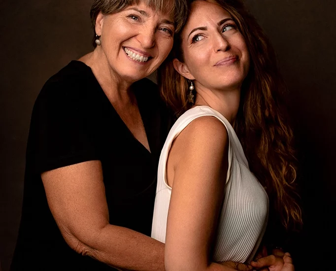 Foto ritratto a colori di due donne, mamma e figlia, che si abbracciano e sorridono. Fotografia ritrattistica a colori Trieste