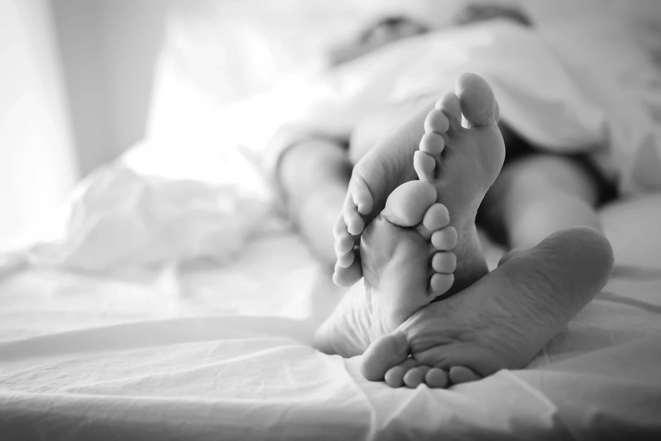 Fotografia Boudoir bianco e nero di coppia a letto con dettaglio sui piedi. Fotografia in bianco e nero Italia