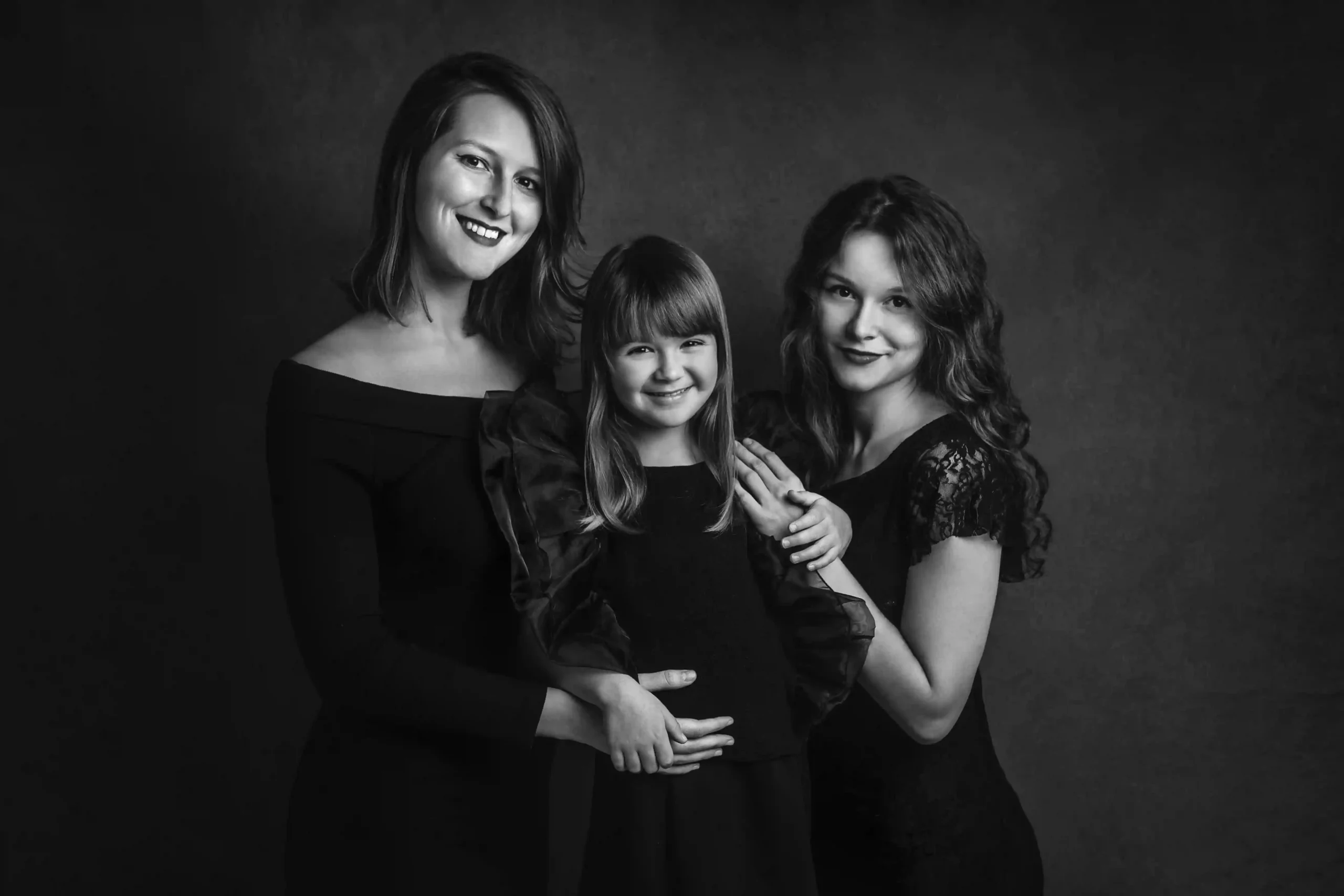 Foto ritratto di famiglia tra sorelle in bianco e nero, tutte vestite di nero che sorridono. Fotografia ritratto Italia