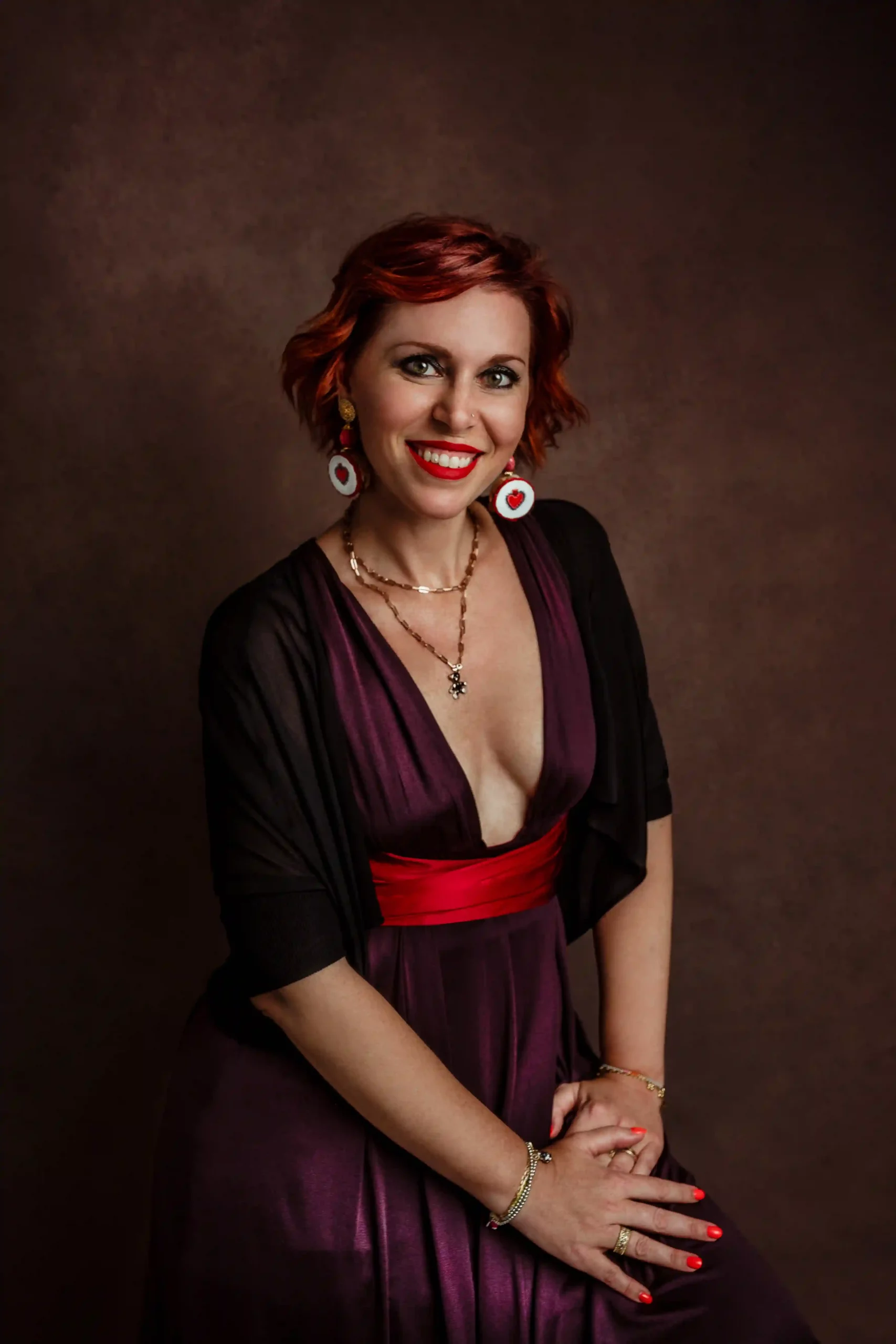 Foto ritrattistica a colori di una donna con un vestito viola e una cintura rossa che sorride. Fotografia a colori Italia
