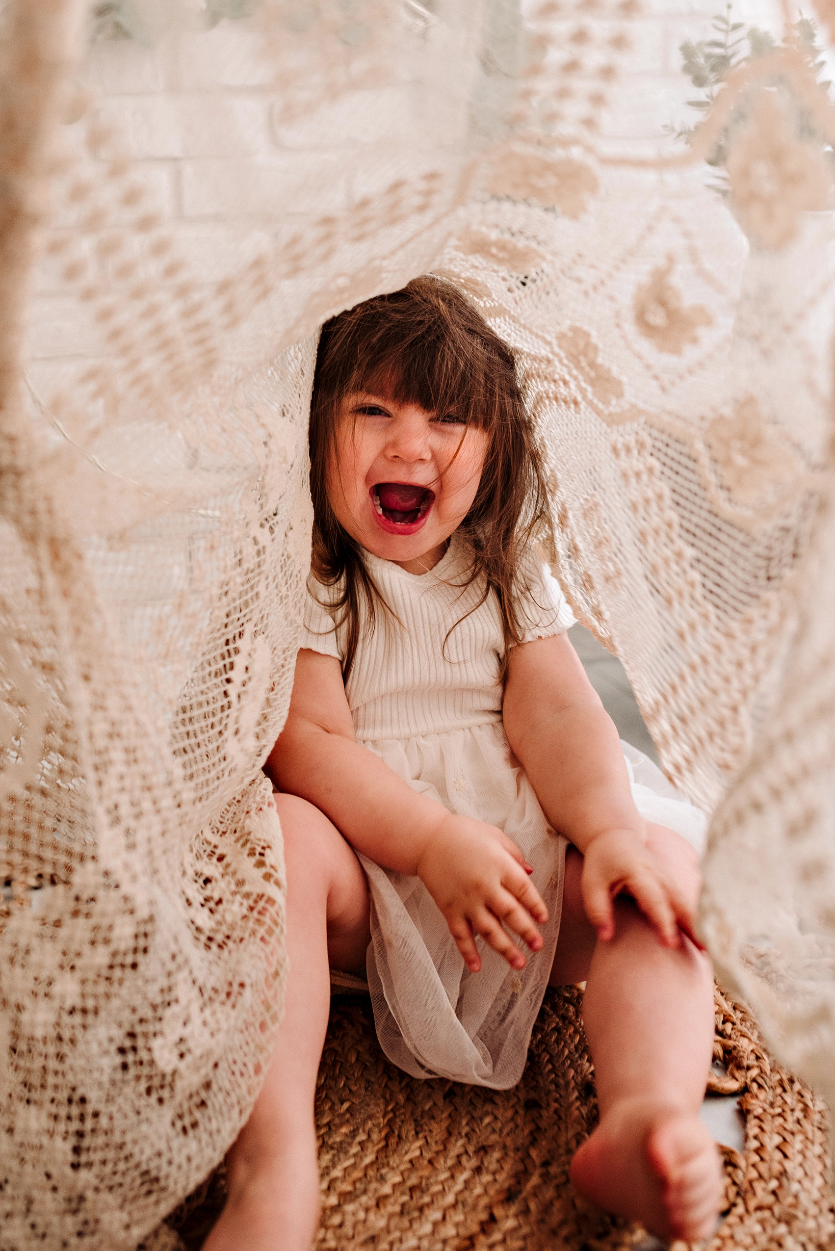 Foto ritrattistica a colori di una bambina sotto una coperta di pizzo bianca. Fotografia ritratto a colori di una bambina sotto coperta di pizzo Trieste